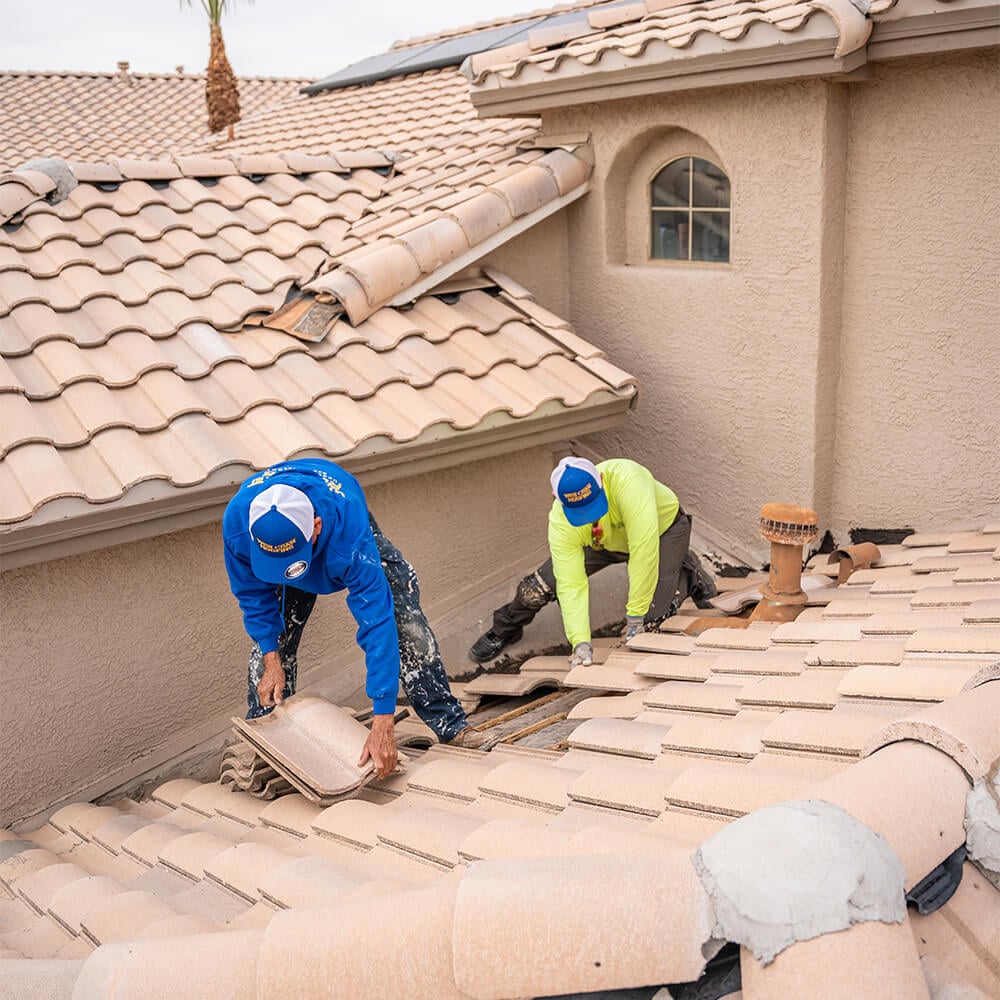 two roofing contractors for West Coast Roofing repairing a roof